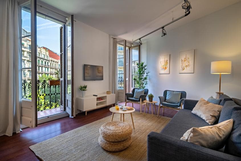Salón luminoso de un piso de Barcelona con balcón a la calle